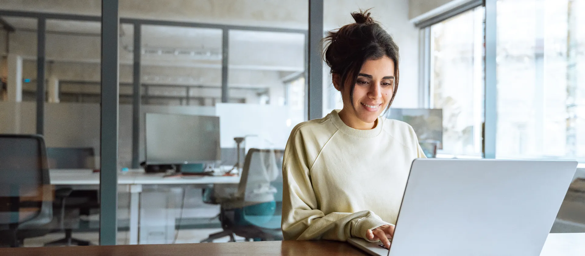 Lächelnde junge Geschäftsfrau, die in einem Büro an ihrem Laptop arbeitet. 