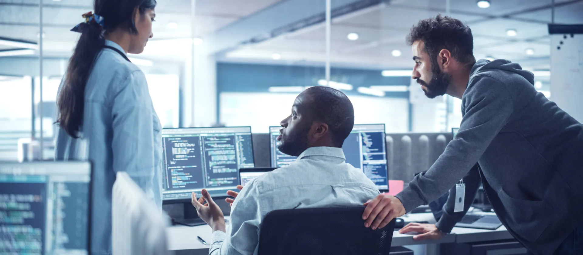 Team working at multiple monitors displaying SAP-related system and program code, representing SAP S/4HANA transformation, integrated business planning, master data governance and analytics solutions.