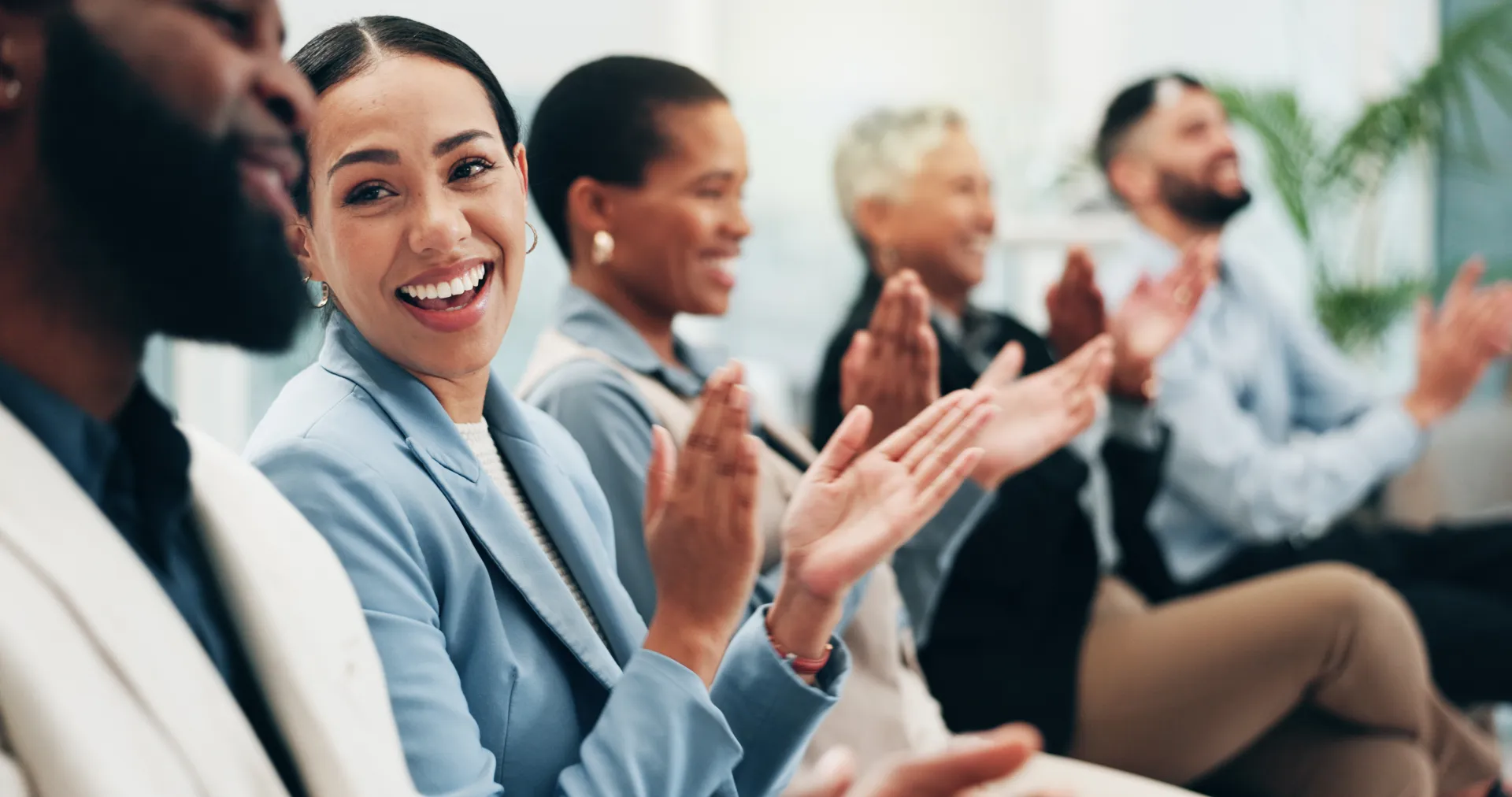 Group of people smiling and applauding in a professional setting, symbolizing successful projects, customer achievements and positive collaboration for success stories.