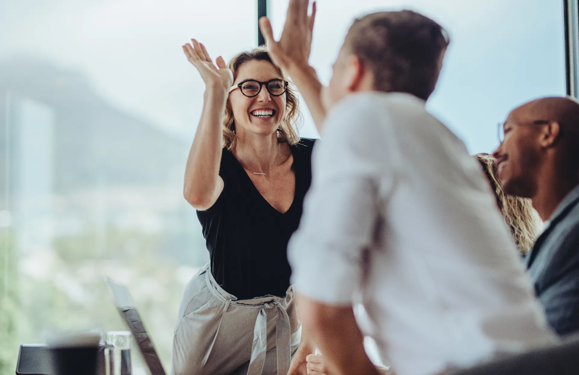 Symbolic image for corporate values Passionate – High-five between colleagues in a meeting.